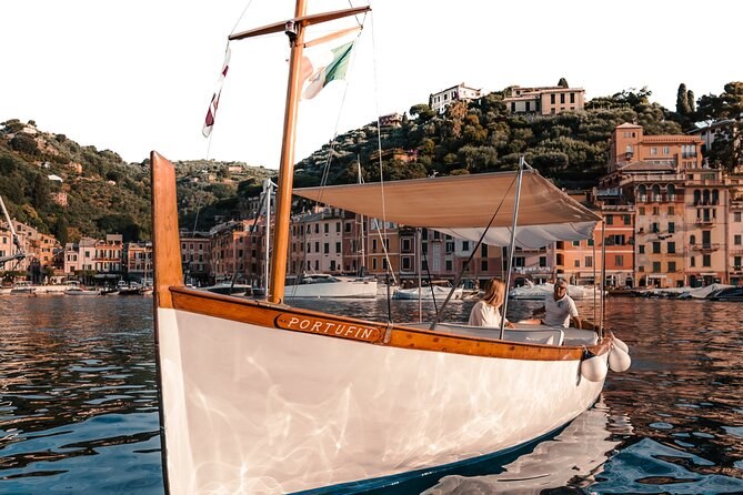 A white wooden boat with a canvas awning in a harbour of painted houses