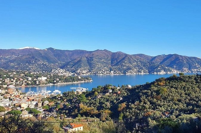 A wide gulf and its seaside town below wooded hills and mountains