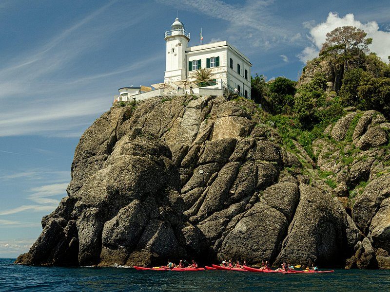 A white lighthouse on a dark rock at the tip of a headland