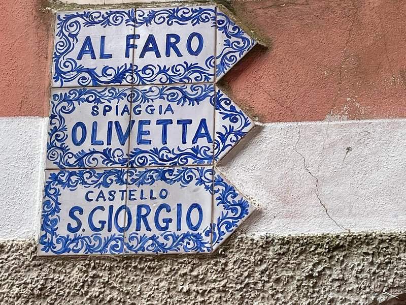 Painted tiles on a wall pointing the way to the lighthouse, a beach and a church