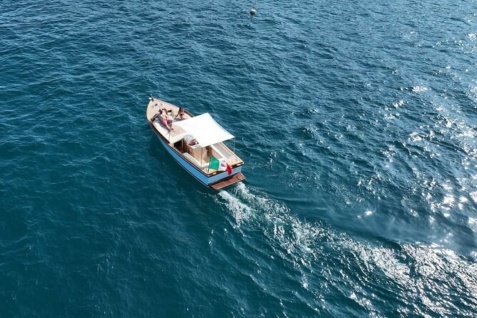 A wooden motorboat crossing open blue sea, seen from above