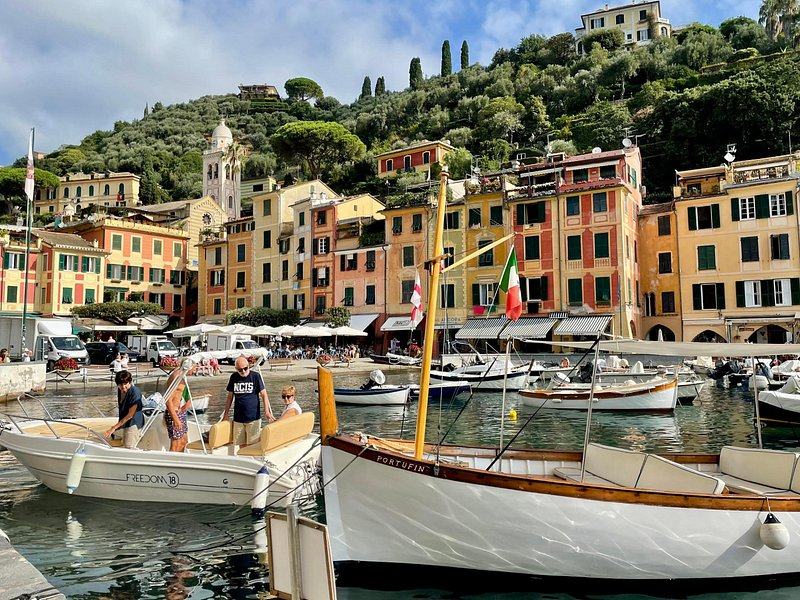 Wooden fishing boats tied up in a small harbour below painted houses and a church tower
